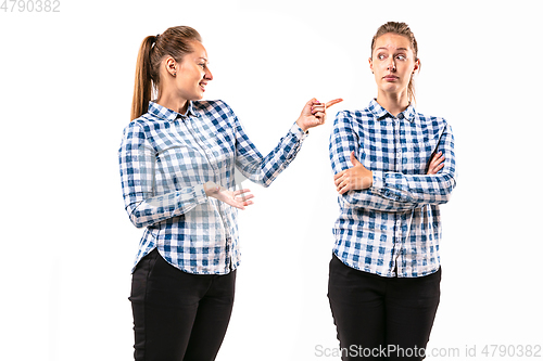 Image of Young handsome woman arguing with herself on white studio background.