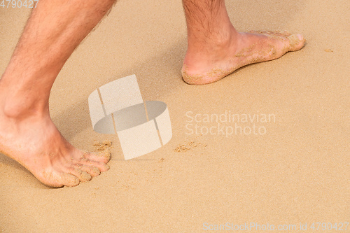 Image of male bare feet in the wet sand