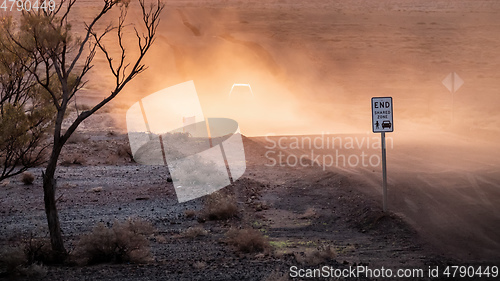 Image of car on a dusty unsealed road in sunset light mood