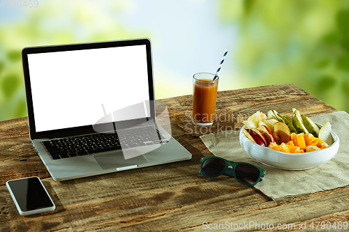 Image of Blank laptop on a wooden table outdoors, mock up