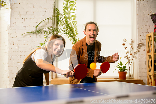 Image of Young people playing table tennis in workplace, having fun