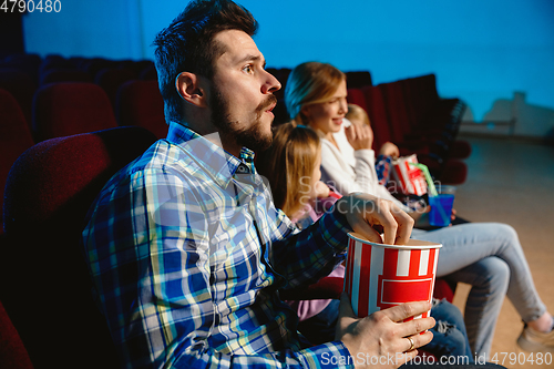 Image of Young caucasian family watching a film at a movie theater