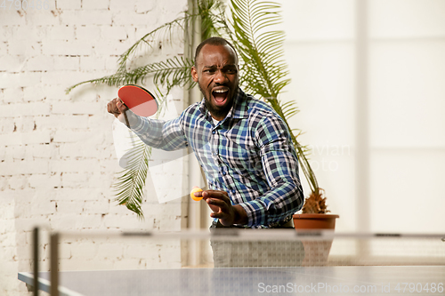 Image of Young man playing table tennis in workplace, having fun