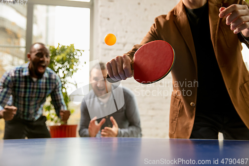 Image of Young people playing table tennis in workplace, having fun