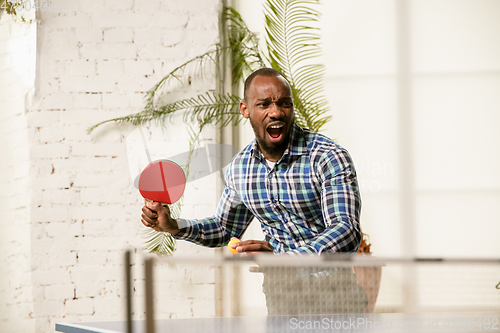 Image of Young man playing table tennis in workplace, having fun