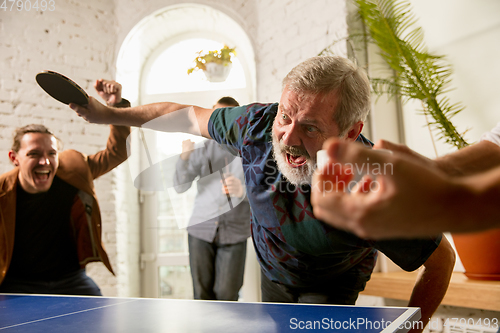 Image of Young people playing table tennis in workplace, having fun