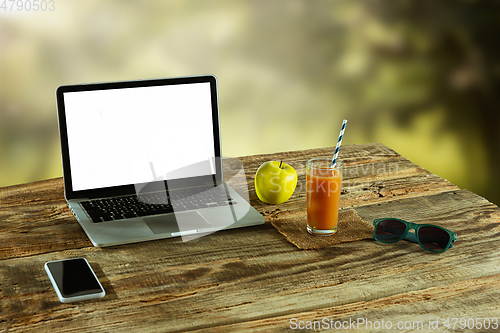 Image of Blank laptop on a wooden table outdoors, mock up