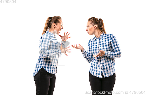 Image of Young handsome woman arguing with herself on white studio background.