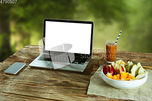 Image of Blank laptop on a wooden table outdoors, mock up