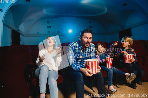 Image of Young caucasian family watching a film at a movie theater