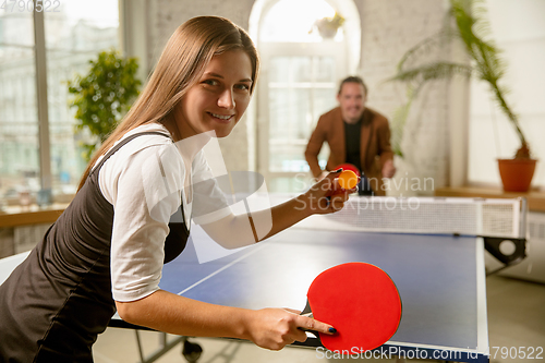 Image of Young people playing table tennis in workplace, having fun