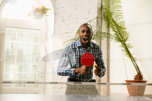 Image of Young man playing table tennis in workplace, having fun