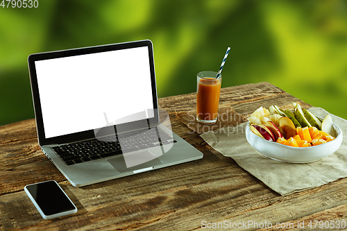 Image of Blank laptop on a wooden table outdoors, mock up