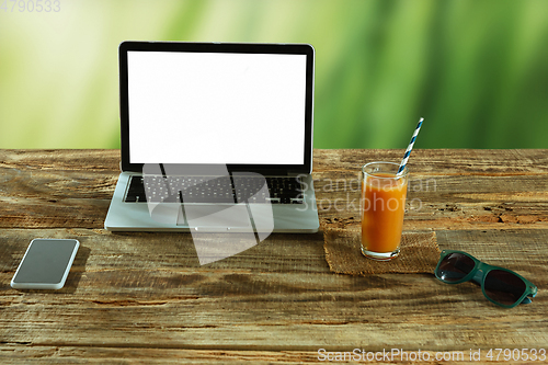Image of Blank laptop on a wooden table outdoors, mock up