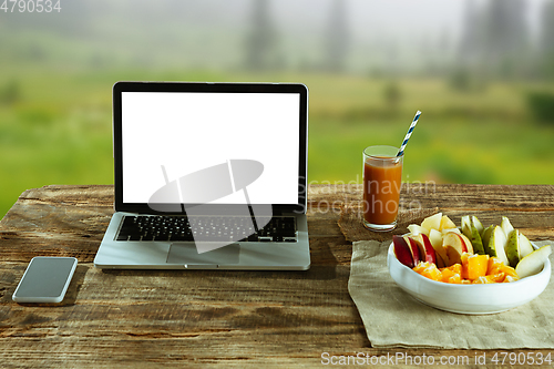 Image of Blank laptop on a wooden table outdoors, mock up