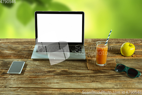 Image of Blank laptop on a wooden table outdoors, mock up