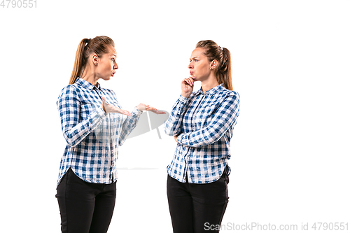 Image of Young handsome woman arguing with herself on white studio background.