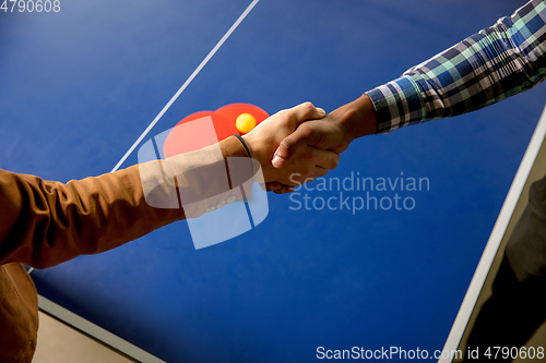 Image of Young men playing table tennis in workplace, having fun