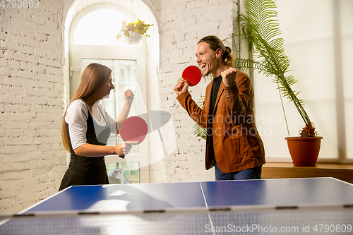 Image of Young people playing table tennis in workplace, having fun