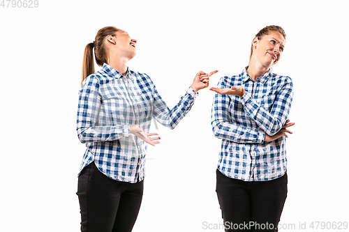 Image of Young handsome woman arguing with herself on white studio background.