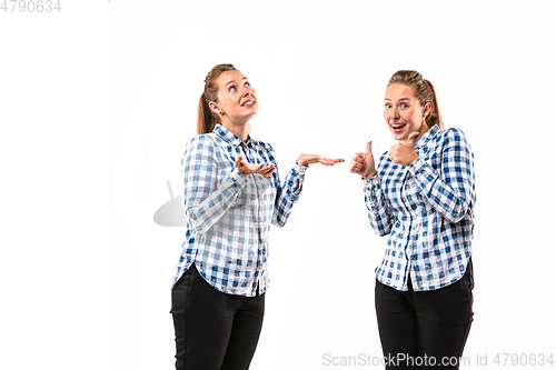 Image of Young handsome woman arguing with herself on white studio background.