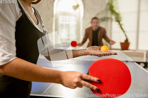 Image of Young people playing table tennis in workplace, having fun