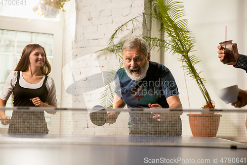 Image of Young people playing table tennis in workplace, having fun