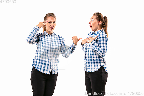 Image of Young handsome woman arguing with herself on white studio background.