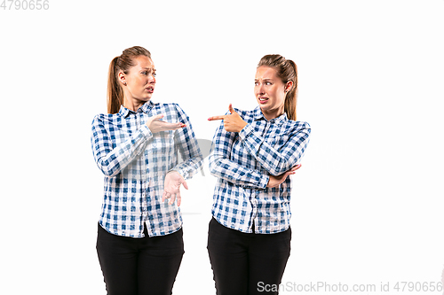 Image of Young handsome woman arguing with herself on white studio background.