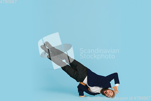 Image of Businessman having fun dancing break dance on blue background at work