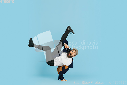 Image of Businessman having fun dancing break dance on blue background at work
