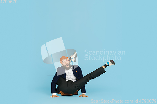 Image of Businessman having fun dancing break dance on blue background at work