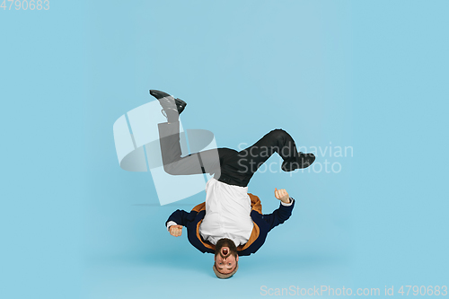 Image of Businessman having fun dancing break dance on blue background at work