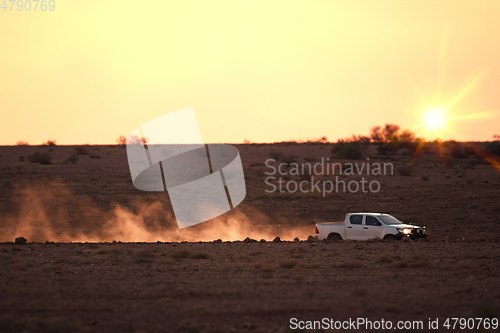 Image of car on a dusty unsealed road in sunset light mood