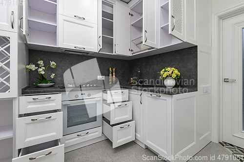 Image of Open doors and drawers open at modern white kitchen