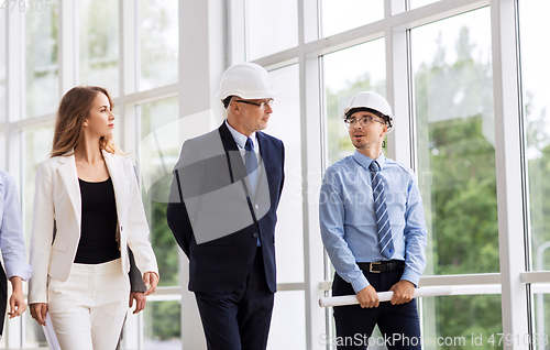 Image of business team in helmets walking along office