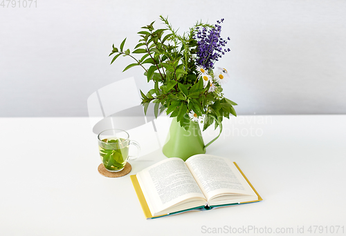 Image of herbal tea, book and flowers in jug on table