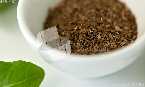 Image of close up of dry basil seasoning in white cup