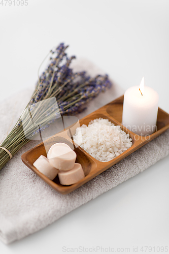 Image of sea salt, soap, candle and lavender on bath towel