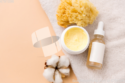 Image of body butter, essential oil, sponge on bath towel