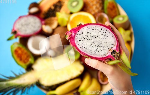 Image of hand holding half of dragon fruit over blue