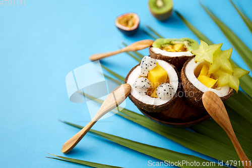 Image of mix of exotic fruits in coconut shells with spoons