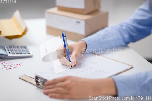 Image of woman with clipboard and parcels at post office