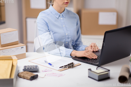 Image of woman with laptop and clipboard at post office