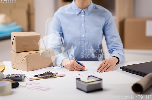 Image of close up of woman filling postal form at office