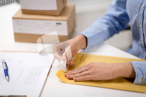 Image of woman removing sticker from envelope with parcel