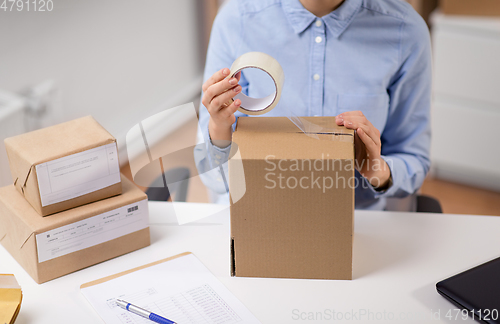 Image of woman packing parcel box with adhesive tape