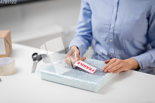 Image of woman sticking fragile mark to wrap at post office