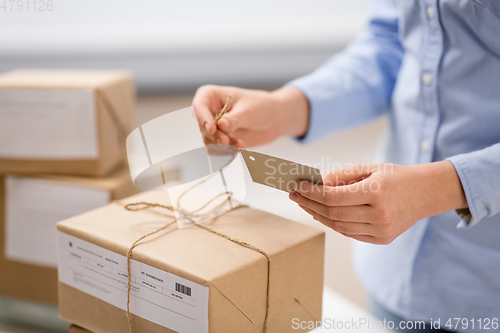 Image of woman packing parcel and tying tag at post office