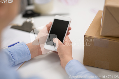 Image of hands with smartphone and parcels at post office